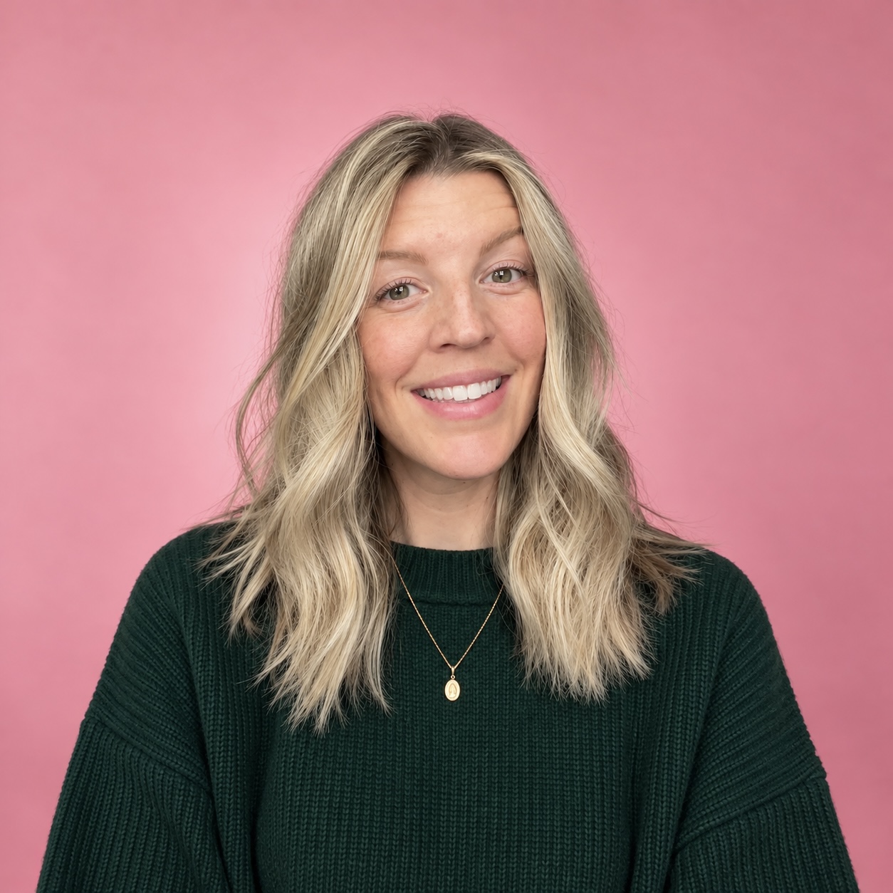 Kaleigh Hyde in a forest green sweater against a pink backdrop